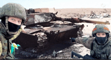 two soldiers standing in front of a tank with arabic writing on the bottom