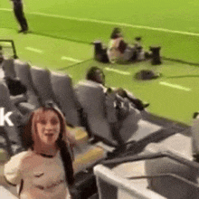 a woman with a prosthetic arm is standing in a stadium watching a game .