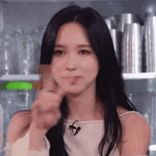 a woman with long black hair is making a funny face and giving a thumbs up .