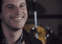 a man is smiling in front of a microphone that says nzos