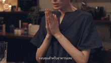 a woman in a blue shirt with her hands folded in front of a sign that says ' chinese ' on it