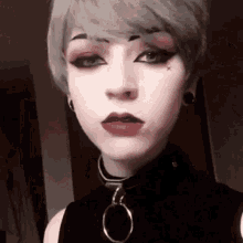 a close up of a woman 's face wearing a choker and earrings .
