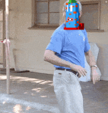 a man wearing a blue shirt and white pants has a toy rocket on his head