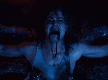 a woman with a necklace around her neck is screaming in a dark room
