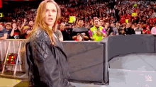 a woman in a black leather jacket stands in front of a crowd with a sign that says ' the next big thing ' on it