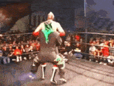 two wrestlers are wrestling in a ring with a crowd watching .