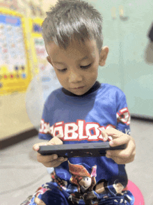 a young boy in a roblox shirt is playing a game