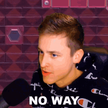 a man wearing a champion shirt says " no way " in front of a microphone