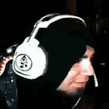 a man wearing headphones and a black hood is smiling .