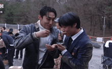 two men are standing next to each other and one of them is wearing a black jacket