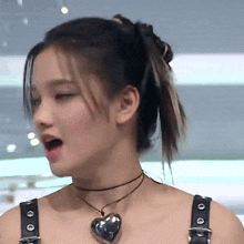 a close up of a woman wearing a choker and a heart pendant .