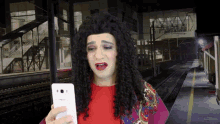 a woman in a wig is holding a phone that says lg on it