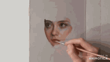 a close up of a person painting a woman 's face with a brush .