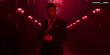 a man in a suit is standing in a dark room with the words pranay varma below him