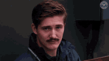 a man with a mustache wears a jacket that says championships