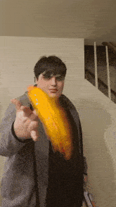 a man in a grey jacket is holding a yellow object in front of his face