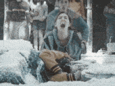 a woman is laying in the snow screaming with her mouth open