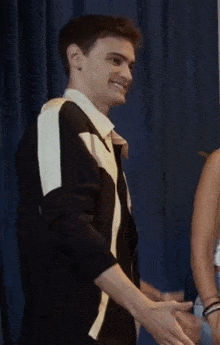 a man wearing a black and white jacket with the word vogue on the front
