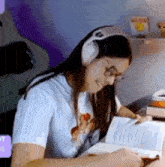 a woman is wearing headphones and reading a book .
