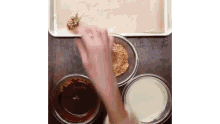 a person is dipping a strawberry in a bowl of chocolate sauce .