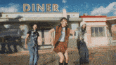 three girls are dancing in front of the diner
