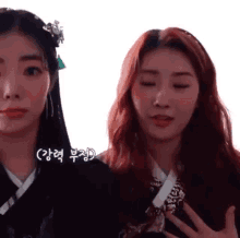 two women with red hair are standing next to each other with their eyes closed and their hands on their chests .