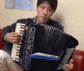 a young man is playing an accordion while sitting on a couch