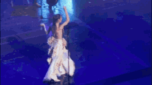 a woman in a long white dress is dancing on a stage .