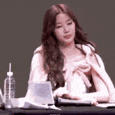 a young woman is sitting at a table with a microphone and a bottle of water .