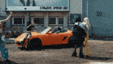 a group of women standing in front of an orange car with a sign that says " stor hate spread love "