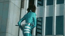 a woman in a blue suit is standing in front of a building .