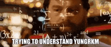 a man with a beard is sitting in front of a chalkboard with mathematical equations on it .