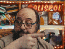 a man wearing headphones is pointing at something in front of a sign that says ' olispol '