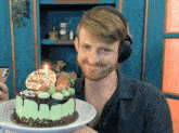 a man wearing headphones is holding a cake that says happy birthday sabrina