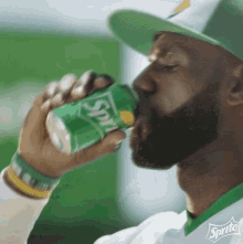 a man with a beard is drinking sprite from a green can