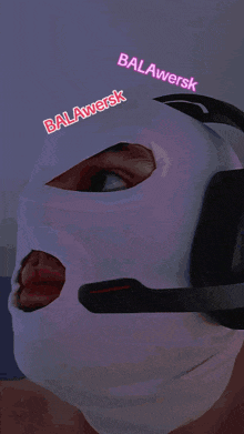 a woman wearing a balawersk mask with pink eyes