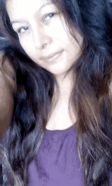 a woman with long dark hair is wearing a purple top