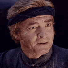 a close up of a man wearing a headband and a blue shirt