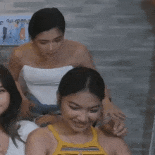 two women are sitting next to each other and one of them is wearing a yellow top .