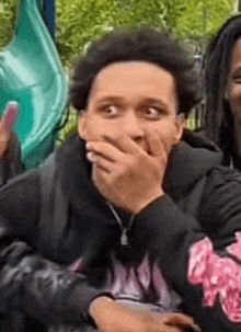 a man is covering his mouth with his hand while sitting next to a woman .