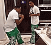 two men standing next to each other with one wearing a white shirt and green pants with the letter e on them