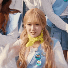 a girl with blonde hair wearing a yellow scarf and a blue sash with a button that says ' i love you '