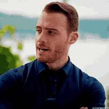 a man with a beard is wearing a blue shirt and tie