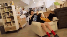 a man and a woman are sitting in a chair looking at their phones