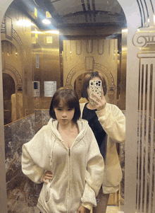 two girls are taking a picture of themselves in an elevator with a phone that says ' casetify ' on it