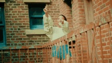 a woman is standing on a balcony with her arms outstretched