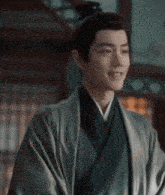 a man in a kimono with a bun on his head is smiling