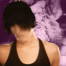 a woman in a black tank top with a purple background