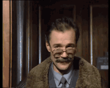 a man with glasses and a mustache is smiling