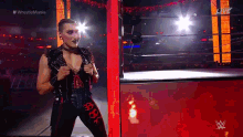 a female wrestler is standing in a wrestling ring holding a sword .